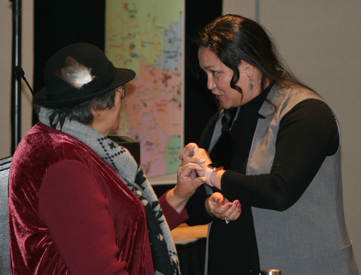 Professional Leader Reconciliation, Michelle Wilsdon holding hands with Elder Irene Morin from Enoch Cree Nation who is wearing a hat with a feather in it.